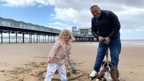 BBC Holidaymakers on beach at Weston, a young girl with her dad and dog