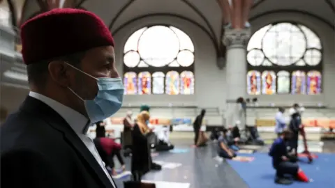 Reuters A Muslim man wearing a face masks prays at a church in Berlin