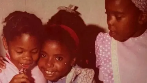 older photo of three young girls smiling at the camera