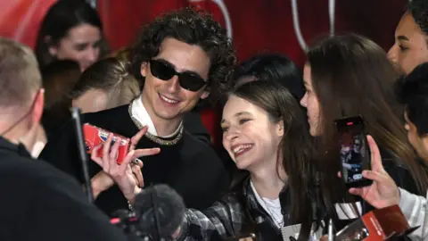 Getty Images Timothée Chalamet takes a selfie with fans on the red carpet