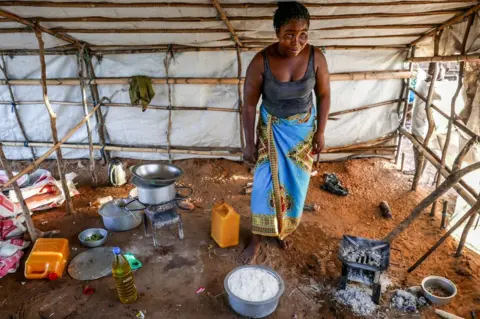 EPA A woman prepares a meal with rice, aid from Caritas Mozambique, for a family with 30 displaced people, in Pemba, Mozambique, 30 March 2021 (issued on 01 April 2021).