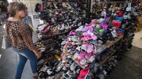 Getty Images A woman shops for Chinese made shoes at a store in the Chinatown area of Los Angeles, California on August 24, 2019