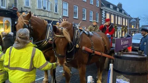 Shannon Eustace/BBC Two large brown horses pulling a cart on which a man in Tudor dress is sitting