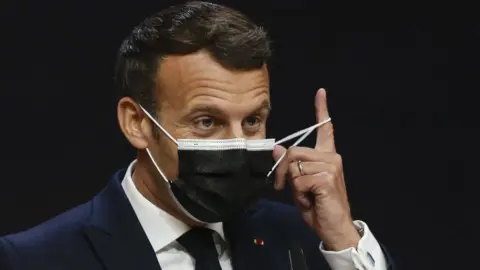 AFP France's President Emmanuel Macron takes off his facemask before giving a press conference during the European Social Summit hosted by the Portuguese presidency of the Council of the European Union at the Palacio de Cristal in Porto on May 8, 2021