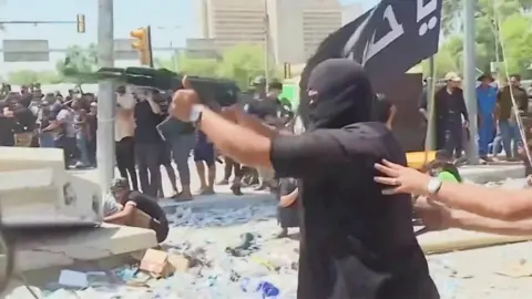 A man shoots a gun during protests in Baghdad