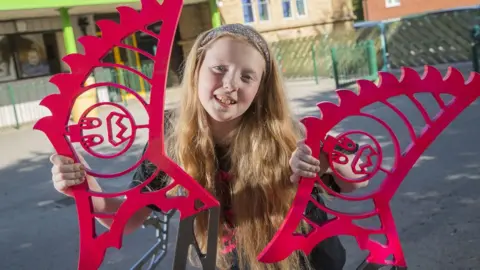 Mike Dean (Eye Imagery) Schoolgirl April Prince holding up parts of the robot she designed and built.