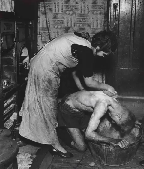 Bill Brandt A photograph of a woman helping a man bathe in a tin bath