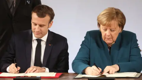 AFP Mr Macron and Mrs Merkel sign the paper copies of the treaty