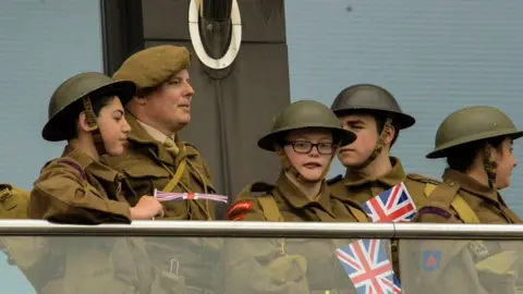 Islanders dressed in military outfits holding union jack flag