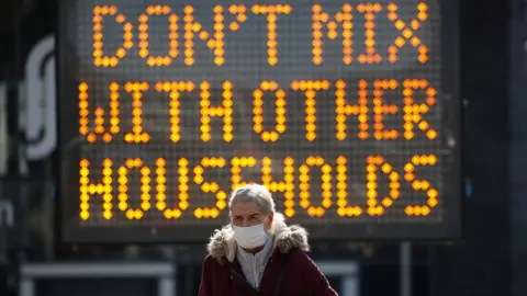 Reuters Woman in front of sign, which reads "Don't mix with other households"