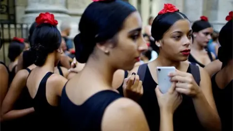 Reuters Cubans with phone