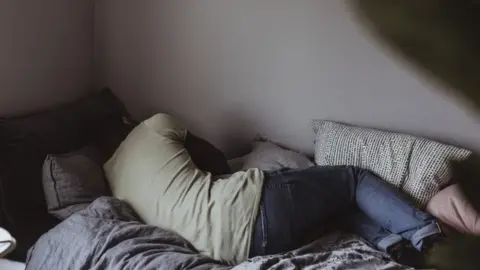 Getty Images Stock image of a woman curled up distressed in bed