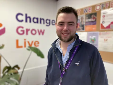 Andy Trigg/BBC Jack Cross in front of Change Grow Live sign