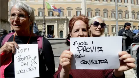 Getty Images Two women hold signs reading "Pro-life, get out of the clinics" during a protest in Rome