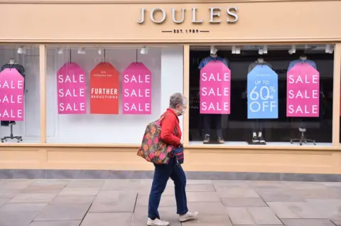 Getty Images Person walks past Joules shop displaying sale