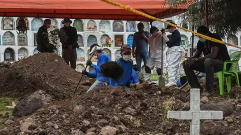 Getty Images Gravediggers and forensic experts search for the remains of victims executed by members of the Colombian army during the Colombian armed conflict, at the cemetery in Dabeiba, Antioquia department, Colombia, on November 10, 2020. -