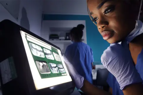 Peter Cade Dentist looking at X-ray of teeth