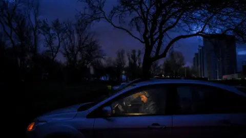 EPA A Ukrainian woman sits in a car after the lights are turned off in Kyiv as part of scheduled power cuts