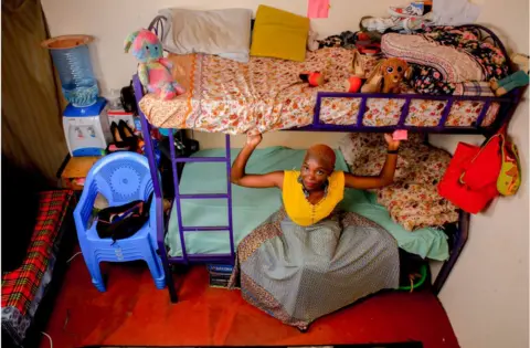 Getty Images Woman in skirt sitting on the bottom rung of a bunkbed in a bedroom.