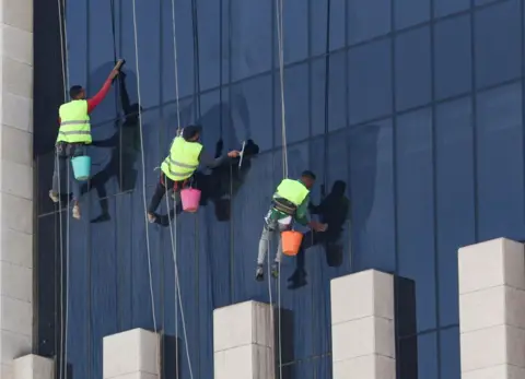 Amr Abdallah Dalsh/Reuters Men abseil from the top of a building to clean its glass front on 21 June.