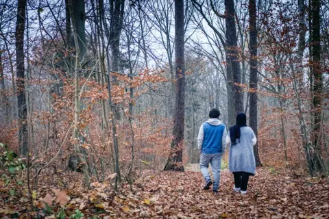 Derrick Evans Serina and her husband walking in the woods outside the camp