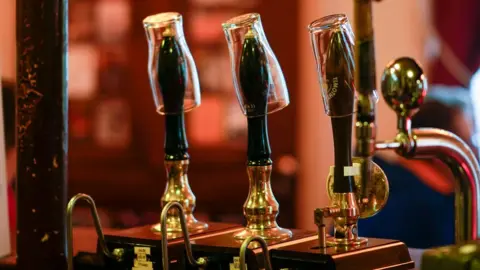 Getty Images Empty pint glasses sit on the top of beer pumps