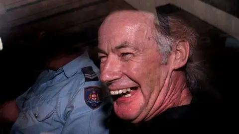 Getty Images Serial killer Ivan Milat laughing in the back of a car