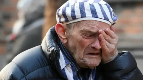 REUTERS A man who survived the Holocaust holds his hand to his face