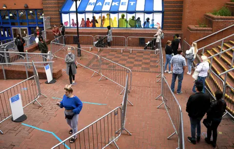 Getty Images Customers follow barriers to safely social distance outside a shopping centre