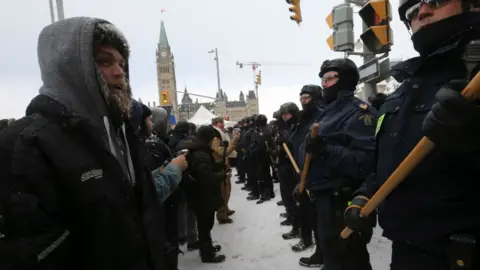 Toronto Star via Getty Images Police form a line as they clear protesters from the intersection of Wellington and Metcalfe.