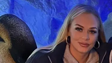 Rebekah Richardson A woman with blond hair and makeup smiling at the camera with a blue background