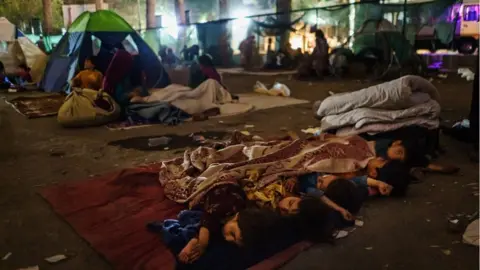 Getty Images Children sleep on cloth covering hard ground in the darkness of the makeshift camp at Shahr-e-Naw Park in Kabul