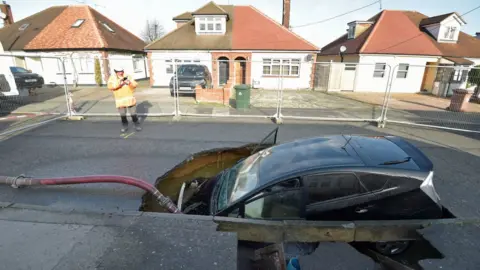 Nick Ansell/PA Media A car in a sinkhole in Brentwood