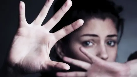 Science Photo Library Woman holds her hand in protective stance