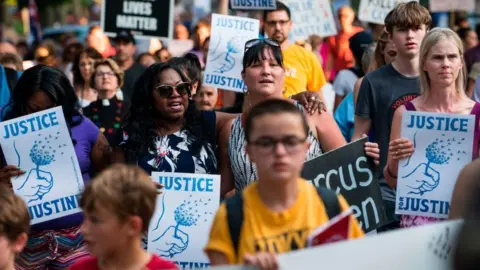 Getty Images A march in Minneapolis in 2017 with protestors holding placards saying "Justice for Justine"