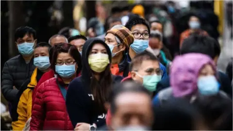 Getty Images People line up in Hong Kong to to purchase face masks from a makeshift stall