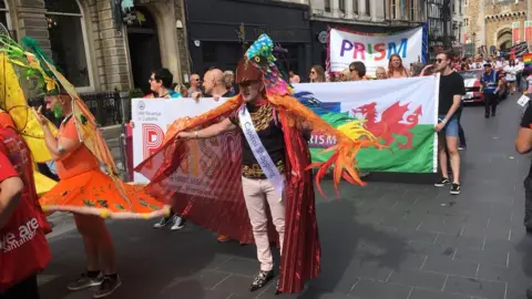 BBC Crowds walk through the street holding flags