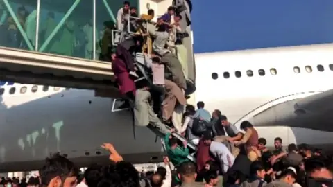 BBC People climbing on to plane at Kabul airport