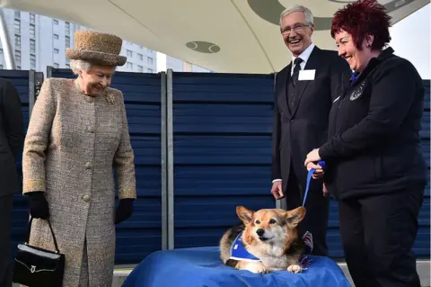 Getty Images Queen Elizabeth II smiles at a Corgi while O'Grady watches on