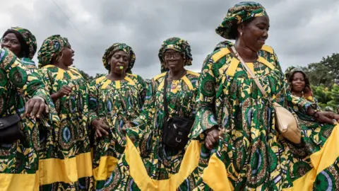 Getty Images Rural women in floral-green outfits dancing.
