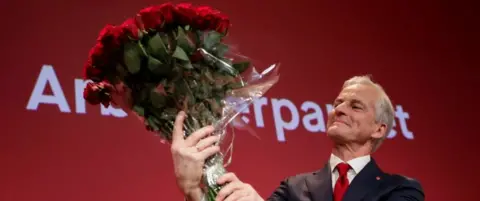 Reuters Jonas Gahr Stoere holds a bouquet of red roses