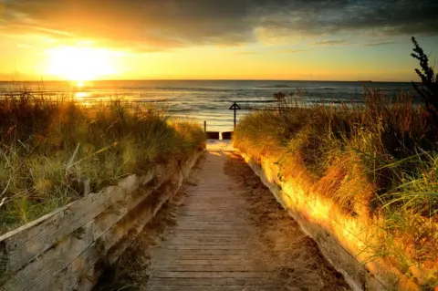 Ian Bell View down path to beach with sun rising over sea