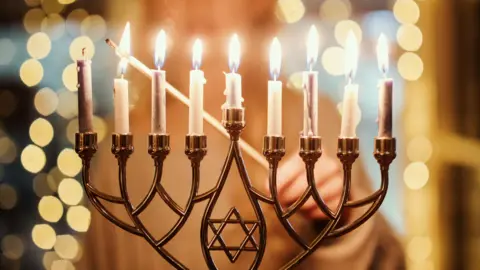 A child lighting the Menorah candles