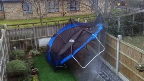 PA A trampoline which has been blown into a garden