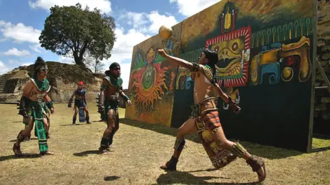 Brooks Kraft via Getty Men play an ancient Mayan ritual game called Juego de Pelota Maya, a Mayan ballgame, at the Iximche ruins.