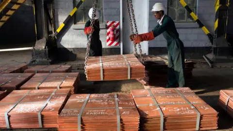 Getty Images Workers in Zambia moving copper sheets