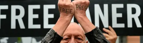 AFP A man with the words "free press" written on the backs of his hands protests at EU headquarters in Brussels on 25 July 2017