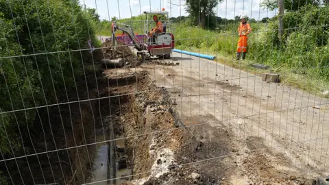 John Fairhall/BBC Engineers from Anglian Water fixing a pipe on Clare Road, Stansfield