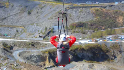 Zip World  A woman hanging from a zip wire