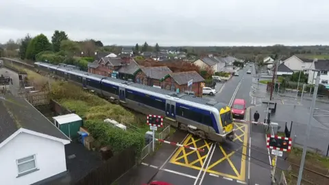 A train moves along a level crossing track in Cullybackey